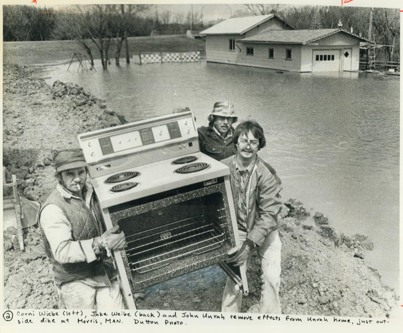 Corni Weibe, left, and Jake Weibe, back, help neighbor John Unrah salvage his stove