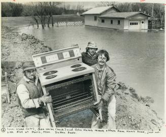 Corni Weibe, left, and Jake Weibe, back, help neighbor John Unrah salvage his stove