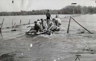 Canadian soldiers ride on a farmer's wagon through flood waters of the Assiniboine river as they travel assists volunteers in plugging dykes in the Ba(...)