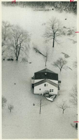 A house in Wheatley, Ont, sits surrounded by water from Lake Erie yesterday, with boats tied at the door