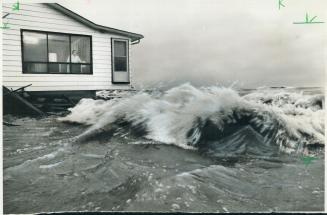 Dorothy Robinson watches from the window as waves hit her lakeshore home at Bay Ridges yesterday