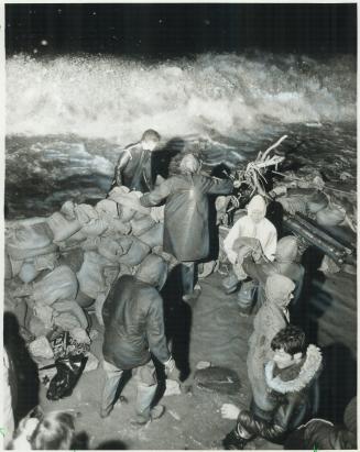 Volunteers worked late into the night building sandbag walls against 10-feet waves which threatened Lakeshore Rd