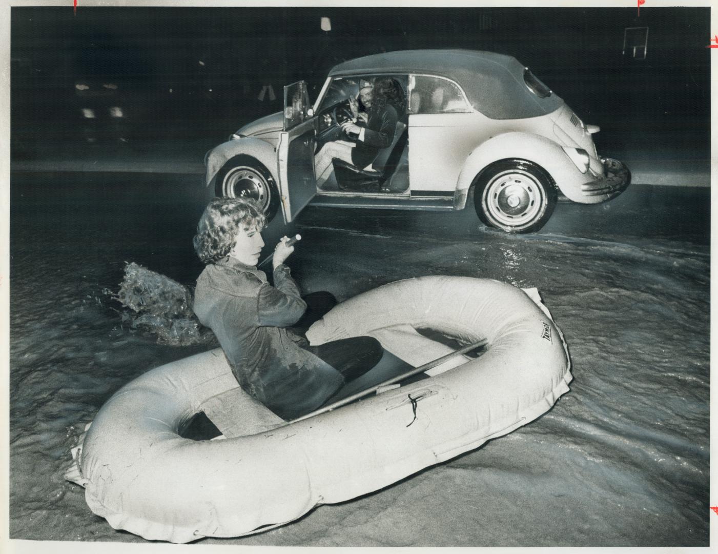 Paddling a rubber boat, 15-year-old Tony Cook passes a car stalled on Queen Frederica Dr. in Mississauga