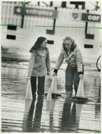 February thaw, Teresa McDougall, 20, (left) and Roxanne Palmer, 25, set markers around gas bar at Trethewey and Jane Sts. in North York during yesterday's flood