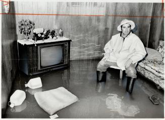 Antonio Fazzalari of Hullmar Dr. wears rubber boots as he inspects his flooded basement