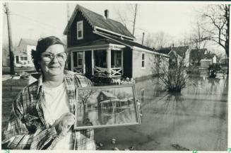 Below, Jean Martin stands in front of her Dresden home holding a photograph of the house during 1968 flood