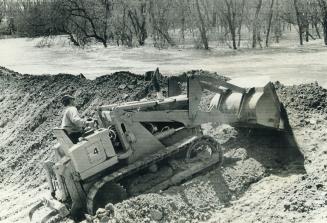 One of the 50 bulldozers at work to mile clay on top of the dikes, which were a few inches to a foot above the water