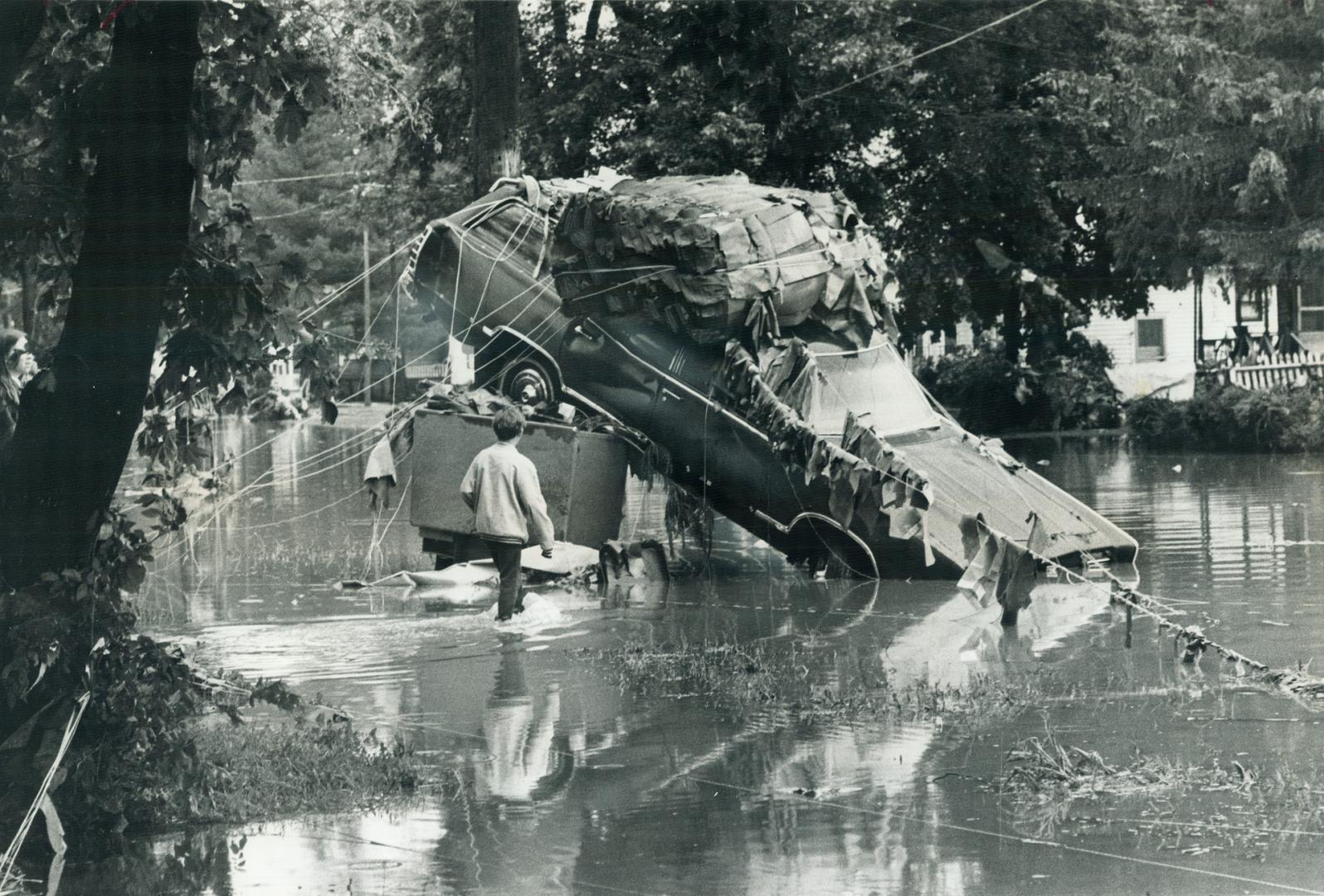 In corning, N.Y., one of hundreds of cars that were pushed through the streets by floodwaters lies entangled with debris as the waters subside. [incomplete]