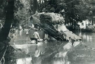 In corning, N.Y., one of hundreds of cars that were pushed through the streets by floodwaters lies entangled with debris as the waters subside. [incomplete]