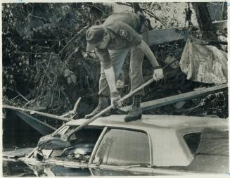 National Guardsman digs mud from a car in Rapid City, S