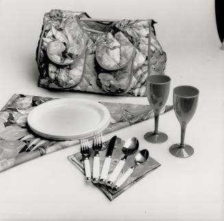 For two. A hamper in a floral print contains plates, cutiery, glasses, napkins, a tablecloth, bottle cozy and corkscrew