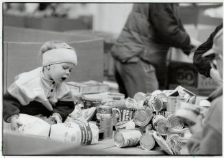 Labor of love: Meagan Sisley, 2, helps her family sort food at the CNE for the Daily Bread Food Bank's Thanksgiving drive