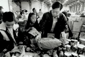 Helping hands: Chris Ho, 35, and his children Wallace, 9, and Candice, 12, pitch in at Exhibition Place yesterday to assist the annual spring food drive, organized by the Daily Bread Food Bank