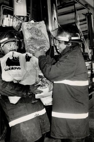 Welcome load for the needy, Firefighters Bruce Rabjohn, left, and Kevin Denby have their hands full at Firehall 1 on Adelaide St. W. in Toronto yester(...)