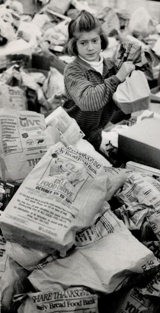 Helping needy: Christine Zida, 10, sorts through donations to last October's Share Thanksgiving Food Drive, Food banks have become fixtures in most urban centres