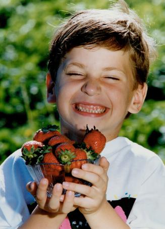 Strawberry season brings a smile, Adam Death, 6, offers up some of the produce from Green Brae Orchards in Ashburn, just north of Ajax
