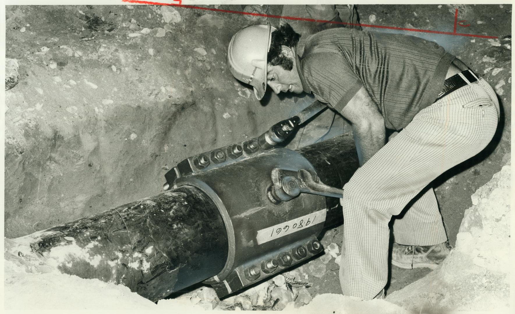 Gas company worker tightens cap on patch over ruptured pipe