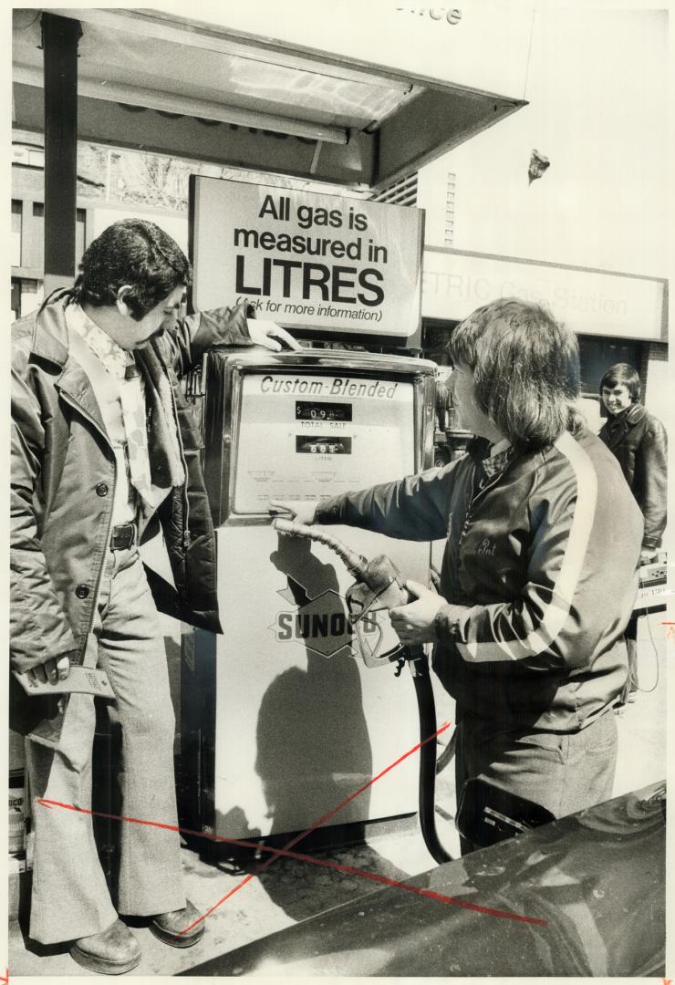 At the first metric service station in Toronto, Pat Boyd serves customer Michaele Conte