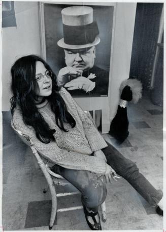 The hippie-with-a-rose, Bev Davies sits in front of life-size poster of W