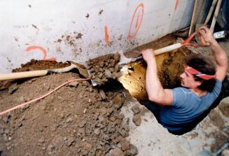 Underpinning basement: Mario Oakes of Innner City Construction in Toronto digs out a section of wall to be underpinned with a new foundation