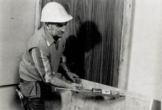 It's easy: Carpenter Tom Brassard applies glue to the back of a wood panel