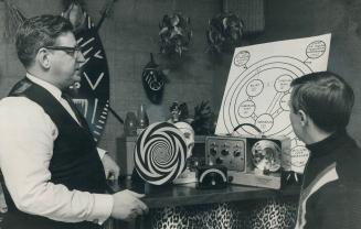 Ralph Albert and son Joe look over some of the equipment he uses in hypnosis experiments, Three items on shelf are, from left, hypnodisc, flash beat metronome and brain wave synchronizer