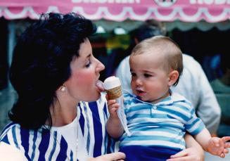 Michael Arnold, 9 months, shares his ice cream cone - at least the part that's not all over his face - with his mother Myra of Mississauga yesterday a(...)