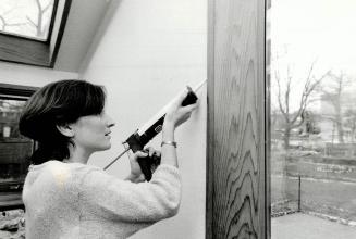 Cosy kitchen: Mary Jo Brennan, an energy conservation inspector with Toronto Hydro, demonstrates how to caulk a door frame in a kitchen in Toronto's East End