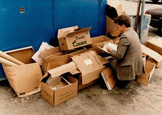 Confidentiality dumped?: Star reporter Donovan looks at confidential documents with names visible, left, from a Scarborough Canada Trust branch found outside recycling plant yesterday