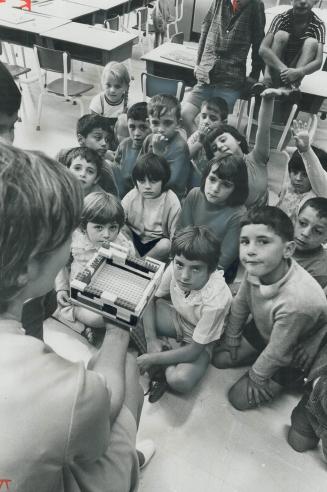 A Group of immigrant children listen, half-comprehending, as teacher Wanda Mathews describes a model building to them in English. Unless these youngst(...)