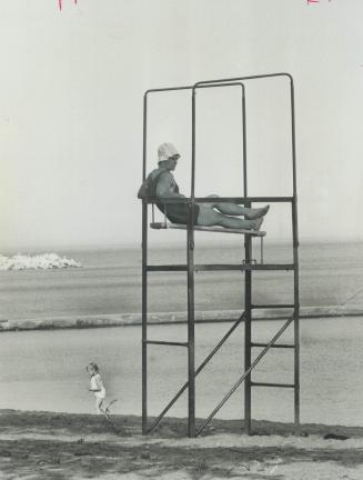 Keeping an eye on things at Woodbine Beach, a lifeguard sits on tower overlooking water as a little girl passes