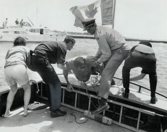 Nearly Exhausted, Jan Groenestein is pulled over the side of patrol boat while Nadine Froud, rescued moments earlier, stands at left. Harbor patrol cr(...)