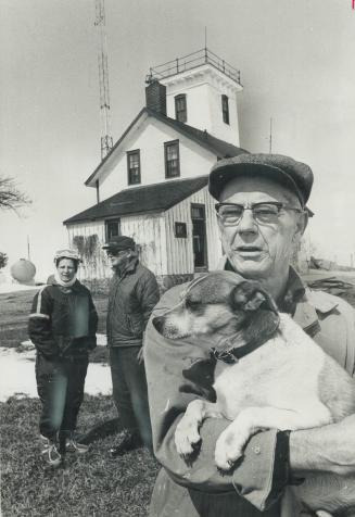 Waiting For Their Ships to come in past the lighthouse marking Hope Island in Georgian Bay, lightkeeper Marvin Graham, 63, holds pet terrier Salty, wh(...)