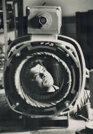 Vern Ramcharitar's face is framed by a 100 horsepower commercial pump he is repairing at Hart Pump Service in Don Mills