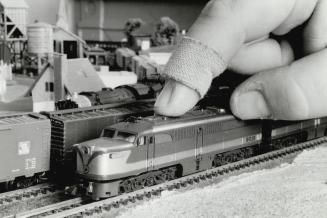 A club member's bandaged finger provides a scale to judge how tiny, and beautifully detailed this model diesel locomotive is