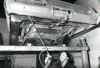 Ronald MacDonald gives underside of car a spray treatment with used motor oil