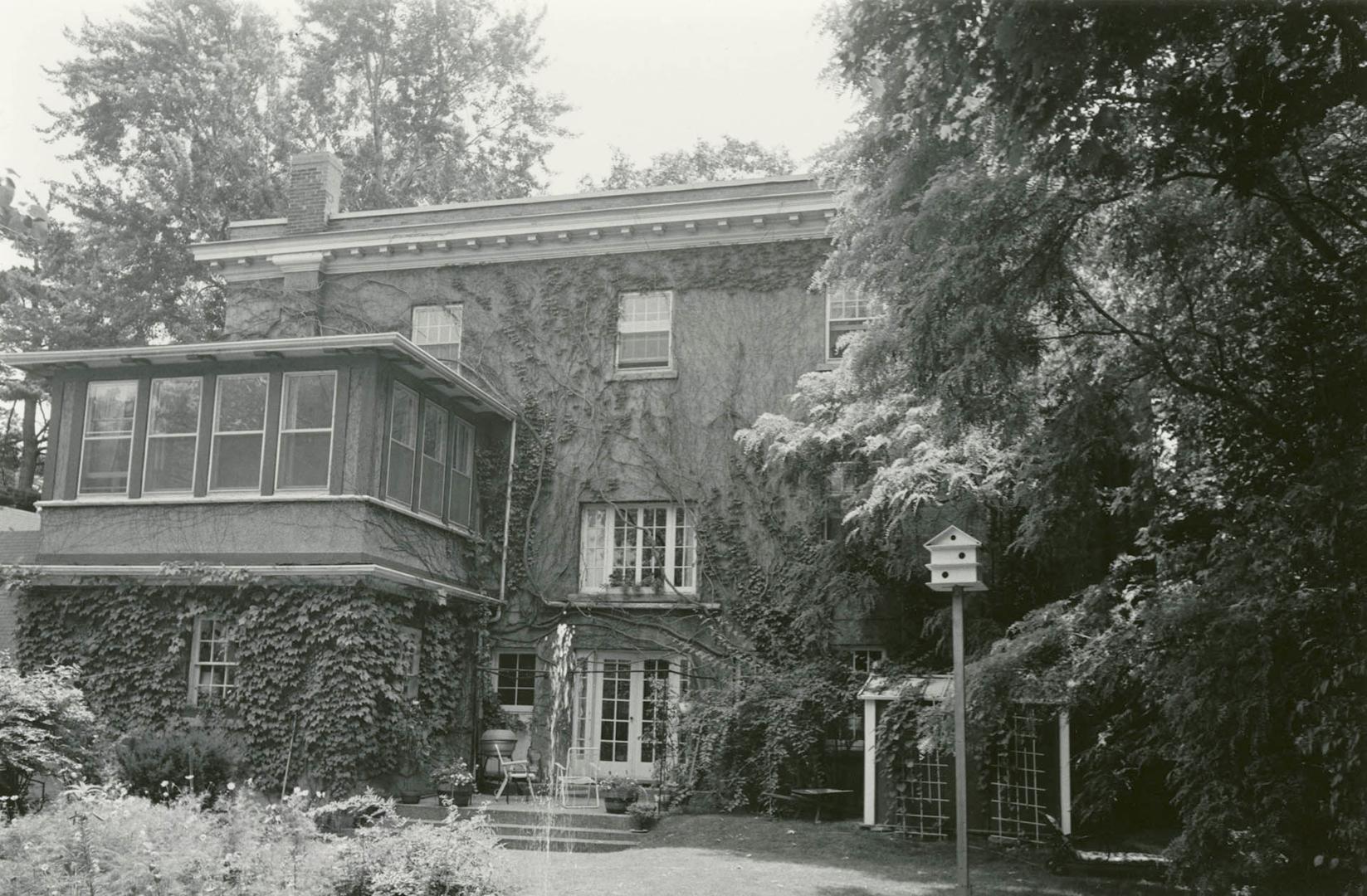 Image shows a three storey residential house with some trees around it. 