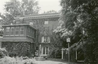 Image shows a three storey residential house with some trees around it. 