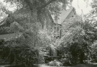 Image shows an extremely limited view of a house. There are a lot of trees around it.