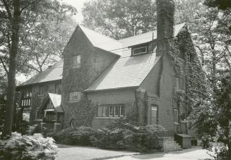 Image shows a three storey residential house with some trees around it.