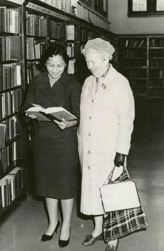 Mrs Leticia Maloles, Colombo Plan trainee from the Philippines, helping a borrower select books at the Beaches Library (autumn, 1960)