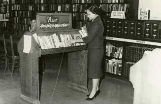 Mrs Leticia Maloles, Colombo Plan trainee from the Philippines, arranging the new book display at Beaches Library (autumn, 1960)