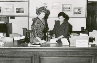 Mrs Leticia Maloles, Colombo Plan trainee from the Philippines, at the main desk, Beaches Library (autumn, 1960) with (Mrs) Louise Umlauf