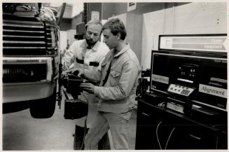 Hands on: Instructor Peter Lokum (left) explains a wheel alignment technique to Al Carr, a student in the new Automotive Service Educational Program at Centennial College