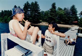 Musical interlude: Flute player Hillary Woodward, 23, from the United Kingdom, entertains Betty Betsedea, 23, from the Northwest Territories, at Operation Raleigh's Island camp in Muskoka
