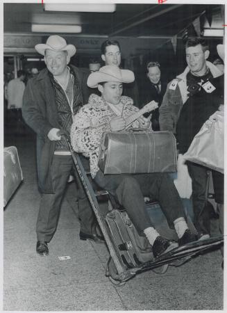 A Weary westerner is wheeled on a baggage cart as Grey Cup fans arrived at Union Station this morning on the 7 o'clock train from Vancouver