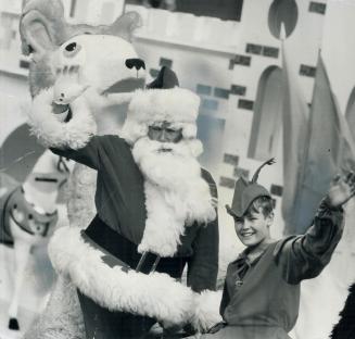Santa waves Hello to Toronto as he stands in splendor beside an elfin aide, 13-year-old Robert Phillips