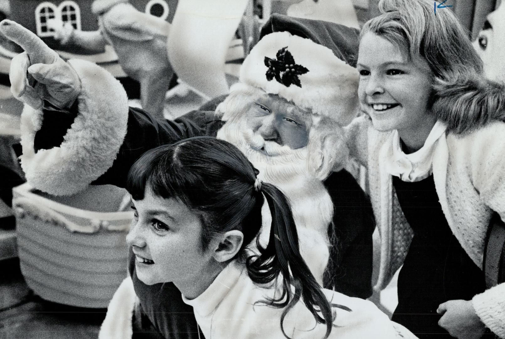 Santa shows Beverley Clark, Faye Marks features of his colorful parade, Twenty floats, clowns