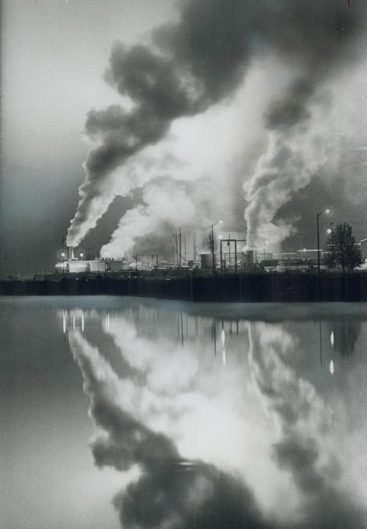 Mirroring a refinery, Spewing smoke into the air, the Texaco refinery at Port Credit is reflected in the glassy waters of an adjoining pond, created b(...)