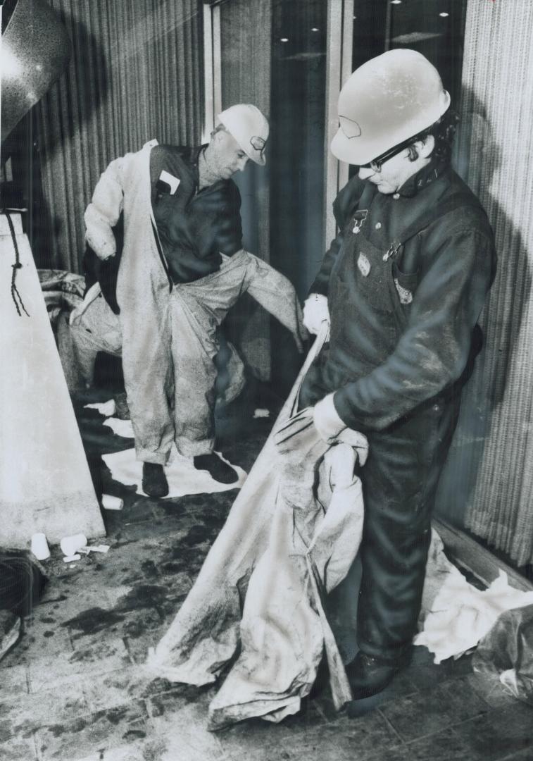 Anti-contamination suits are donned by hydro workers Terry Godfrey (left) and Ron Tasker before they start repairs on transformer after Adelaide St. f(...)